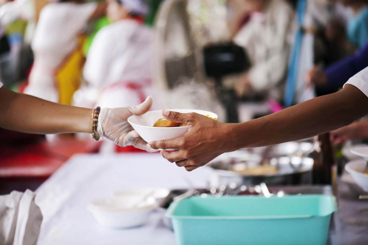 One handing a bowl of food to another