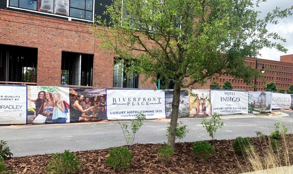 Several fence signs side to side in front of a brick building