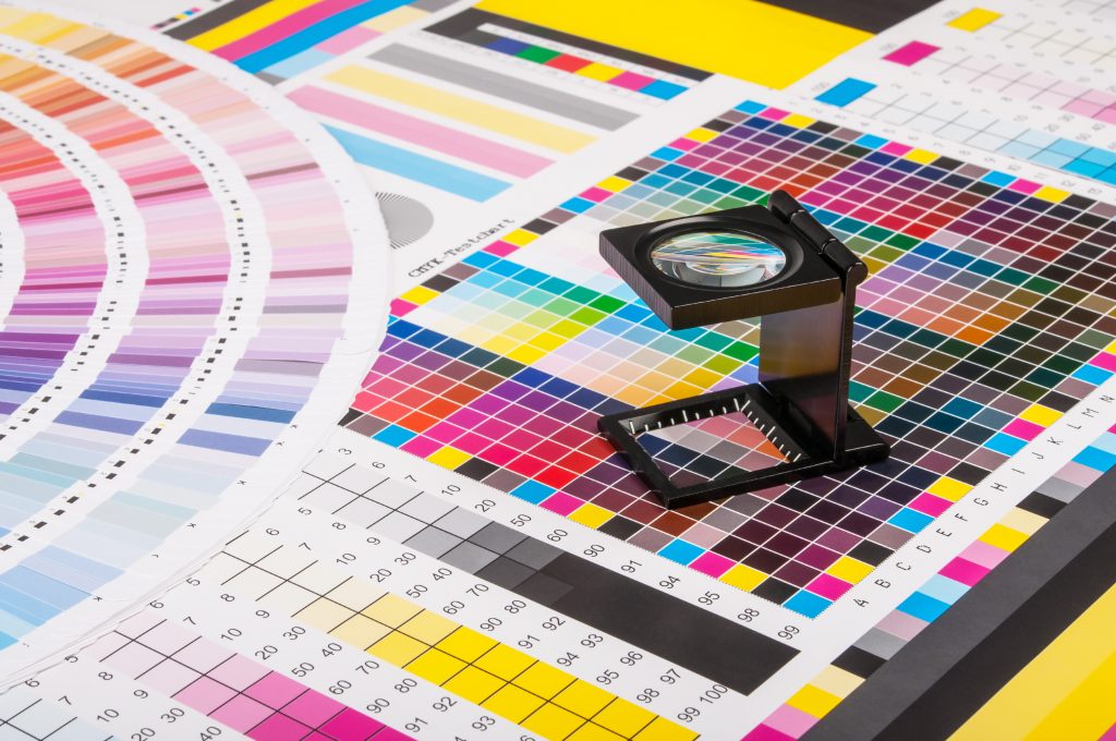 Sheets of paper with color swatches and a loupe on top